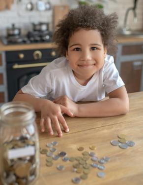 Child counting out coins from a glass Mason jar