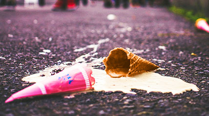 broken ice cream cone with melted ice cream that has fallen on the pavement